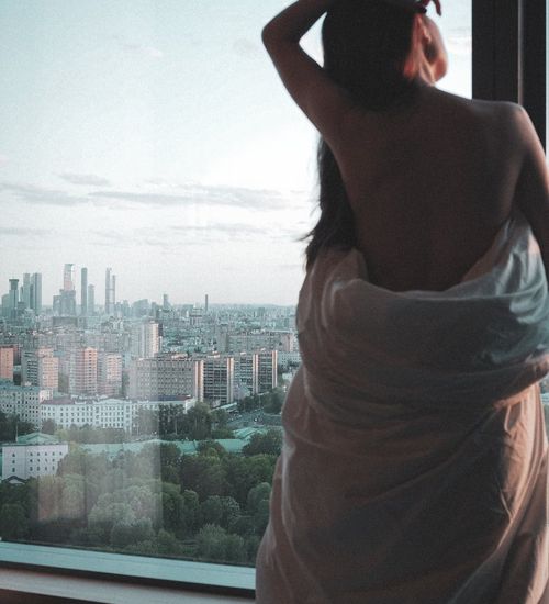 Silhouette of a woman stretching against a window at sunrise.